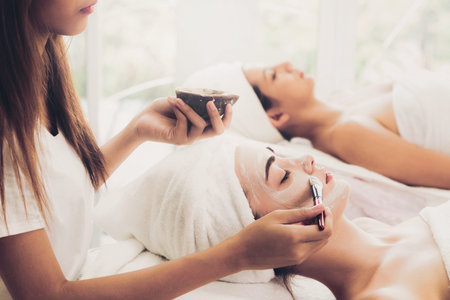 Beautiful woman having a facial cosmetic scrub treatment from professional dermatologist at wellness...
