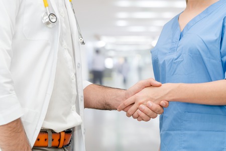 Doctor in hospital handshake with another doctor. Healthcare people teamwork and medical service concept.の写真素材