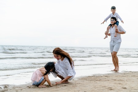 Happy family of father, mother and kids goes vacation on a tropical sand beach in summer.の写真素材