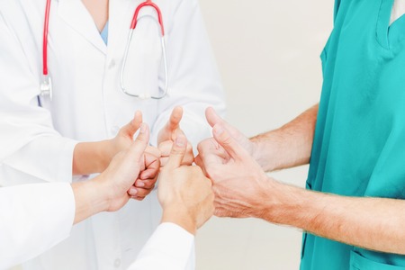 Medical service teamwork - Doctor, surgeon and nurse join hands together.の写真素材