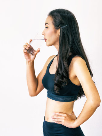 Woman in sportswear drinking water in a fitness gym. Healthy lifestyle and hydration concept.