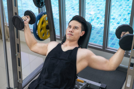 Muscular man bodybuilder in fitness gym training with dumbbells. Healthy lifestyle and bodybuilding...