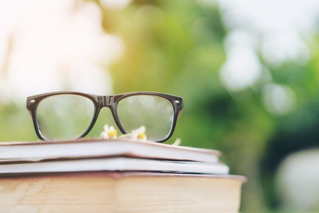 Soft focus retro style books and eye glasses with nature background. Reading and education concept.の写真素材
