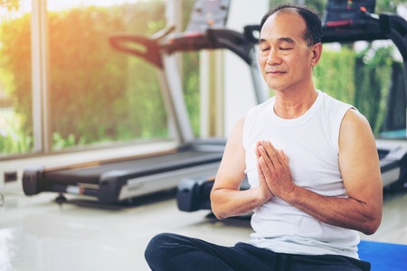 Senior man practice yoga in fitness gym. Mature healthy lifestyle.の写真素材