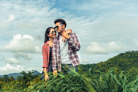 Happy couple take a romantic walk in green grass field on the hills. Travel and honeymoon concept.の写真素材
