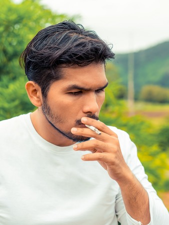 Young man smoking cigarette in the outdoors and nature background.の写真素材