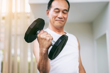 Senior man lifting dumbbell in fitness gym. Senior healthy lifestyle.の写真素材