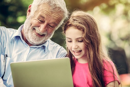 Happy family using laptop computer together in the garden park in summer. Kid education and family activities concept.の写真素材