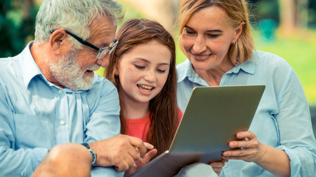 Happy family using laptop computer together in the garden park in summer. Kid education and family activities concept.の写真素材