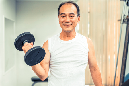 Senior man lifting dumbbell in fitness gym. Senior healthy lifestyle.の写真素材
