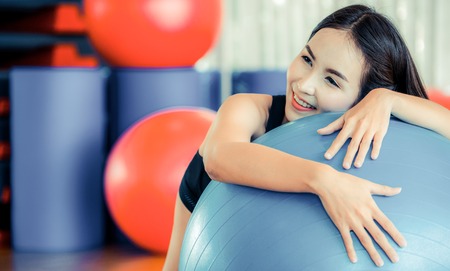 Beautiful young woman in fitness center doing pilates exercise with fitness ball. Healthy lifestyle concept.の写真素材