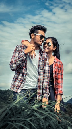 Happy couple take a romantic walk in green grass field on the hills. Travel and honeymoon concept.の写真素材
