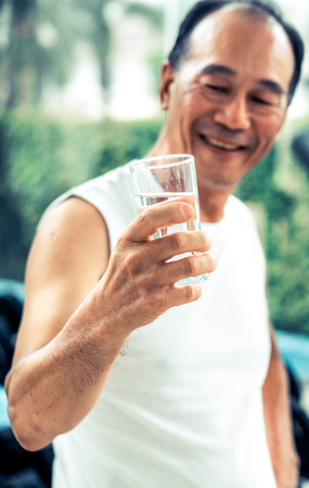 Senior man drink mineral water in gym fitness center after exercise. Elderly healthy lifestyle.の写真素材