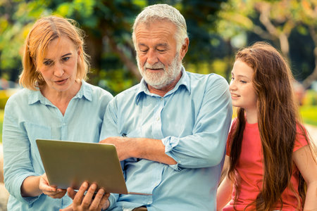 Happy family using laptop computer together in the garden park in summer. Kid education and family...