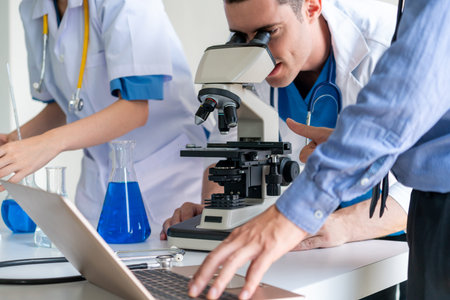 Group of scientists wearing lab coat working in laboratory while examining biochemistry sample in...