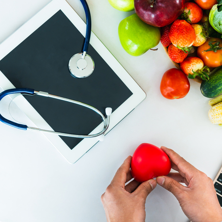 Diet food of fruit and vegetables for cholesterol control with nutritionist hands showing awareness and prevention of heart disease.の写真素材