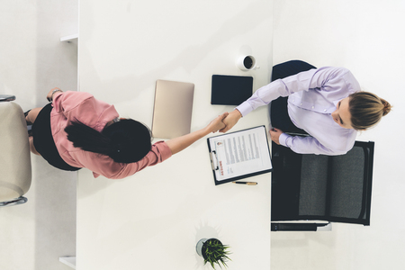 Two young business women in meeting at office table for job application and business agreement. Recruitment and human resources concept.の写真素材