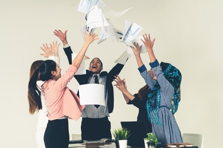 Smiling business people having fun by throwing papers in the air celebrating business success in the modern office.の写真素材