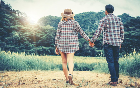 Happy couple take a romantic walk in green grass field on the hills. Travel and honeymoon concept.の写真素材