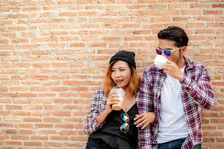 Happy young man and woman drink coffee at the town street. Couple and young people lifestyle.の写真素材