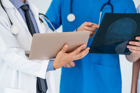 Male doctor looking at x ray film of patient head injury while working with another doctor at the...