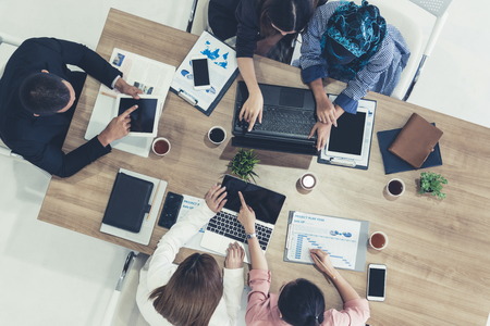 Top view of businessman executive in group meeting with other businessmen and businesswomen in modern office with laptop computer, coffee and document on table. People corporate business team concept.の写真素材
