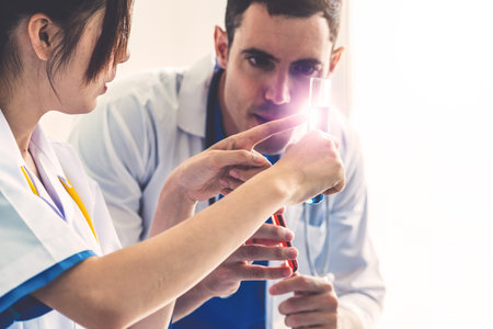 Group of scientists wearing lab coat working in laboratory while examining biochemistry sample in...