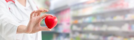 Doctor holding a red heart at hospital office. Medical health care and doctor staff service concept.の写真素材