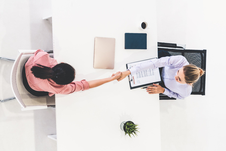 Two young business women in meeting at office table for job application and business agreement. Recruitment and human resources concept.の写真素材
