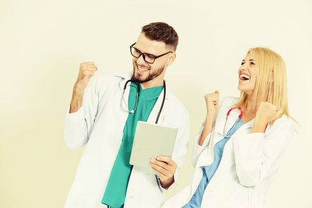 Happy young doctors celebrate success on white background. Medical service and healthcare people concept.の写真素材