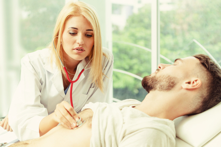 Woman doctor is talking and examining male patient in hospital office. Healthcare and medical service.の写真素材