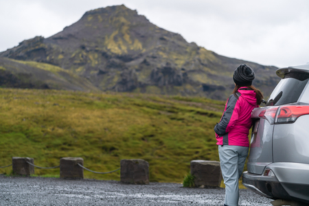 Woman tourist travel by SUV car for road trip in Iceland. The traveler parking the car and enjoy beautiful scenery of mountain landscape in the background. Discovery and exploration.の写真素材