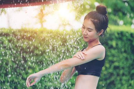 Young woman taking shower at swimming pool in luxury resort hotel. Travel and summer lifestyle.の写真素材