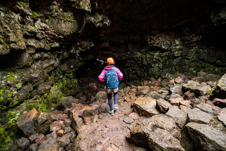 Woman traveler explore lava tunnel in Iceland. Raufarholshellir is a beautiful hidden world of cave. It is one of the longest and best-known lava tubes in Iceland, Europe for incredible adventure.の写真素材