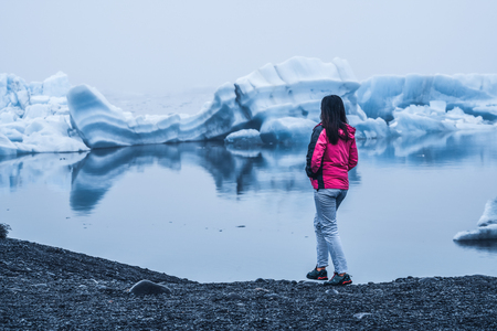 Woman traveler travels to Jokulsarlon beautiful glacial lagoon in Iceland. Jokulsarlon is a famous destination in Vatnajokull National Park, southeast Iceland, Europe. Cold winter ice nature.の写真素材