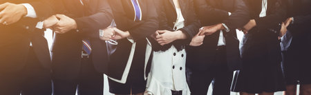 Many happy business people holding hands together with joy and success. Company employee celebrate...