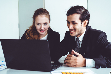 Happy businessman and businesswoman working using laptop computer at the office desk. Business teamwork concept.の写真素材