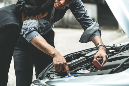 Man help woman fix the car problem. He pop up the car hood to repair the damaged part.の写真素材