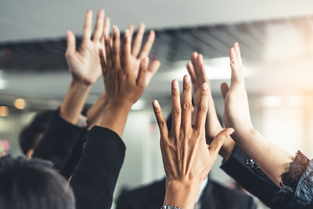 Many happy business people raise hands together with joy and success. Company employee celebrate after finishing successful work project. Corporate partnership and achievement concept.の写真素材