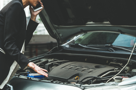 Young businesswoman whose car breakdown uses mobile phone to call for roadside assistance service. Travel and transportation vehicle problem.の写真素材