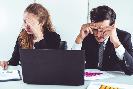 Unhappy serious businessman and businesswoman working using laptop computer on the office desk. Bad business crisis situation and bankruptcy concept.の写真素材