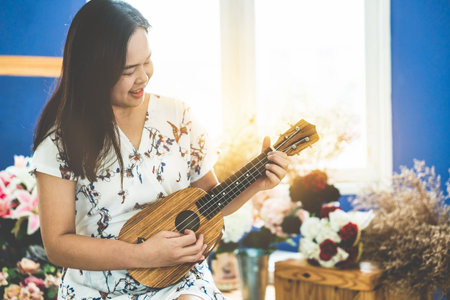 Happy woman musician playing ukulele and singing a song in sound studio. Music lifestyle concept.