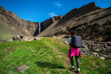 Woman traveler trekking in Icelandic summer landscape at the Hengifoss waterfall in Iceland. The waterfall is situated in the eastern part of Iceland.の写真素材