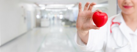Doctor holding a red heart at hospital office. Medical health care and doctor staff service concept.の写真素材