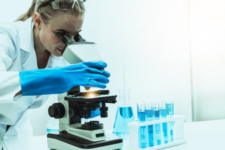 Young woman scientist working in chemical laboratory and examining biochemistry lab sample.