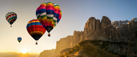Beautiful panoramic nature landscape of countryside mountains with colorful high hot air balloons festival in summer sky.の写真素材