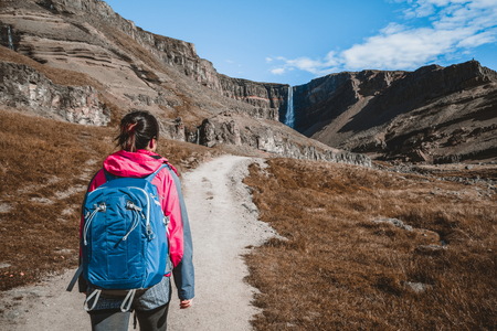 Woman traveler trekking in Icelandic summer landscape at the Hengifoss waterfall in Iceland.の写真素材