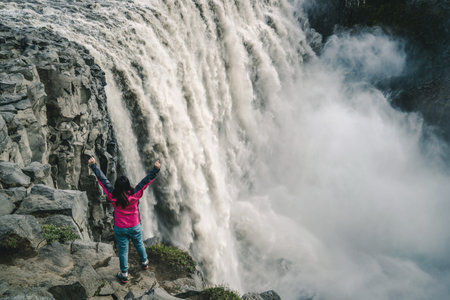 Woman traveler at amazing Iceland landscape of Dettifoss waterfall in Northeast Iceland.