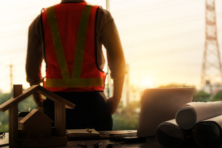 Young man architect or engineer working at desk with designer equipment to make interior design at workplace. Real estate business and civil engineering concept.の写真素材