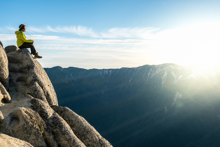 Epic adventure of brave and ambitious hiker trekking activity on wild cliff, pose with panoramic nature mountain landscape. Winner motivation and power discovery travel concept.の写真素材